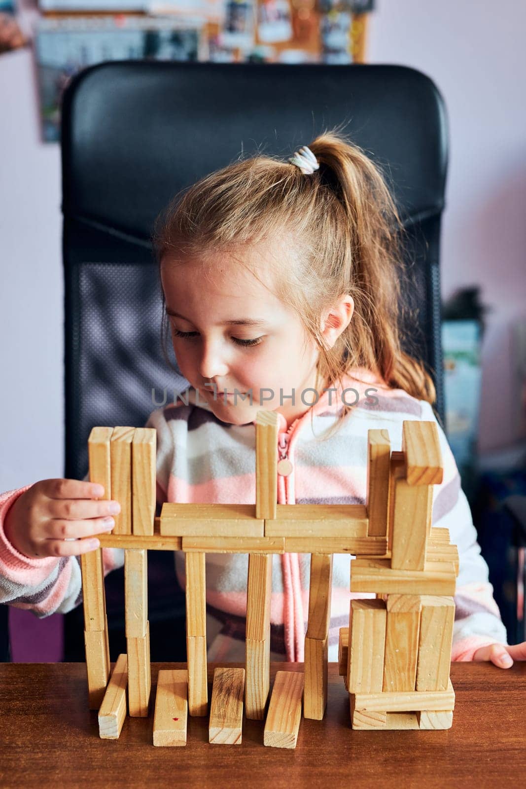 Little girl preschooler playing with wooden blocks toy building a tower. Concept of building a house