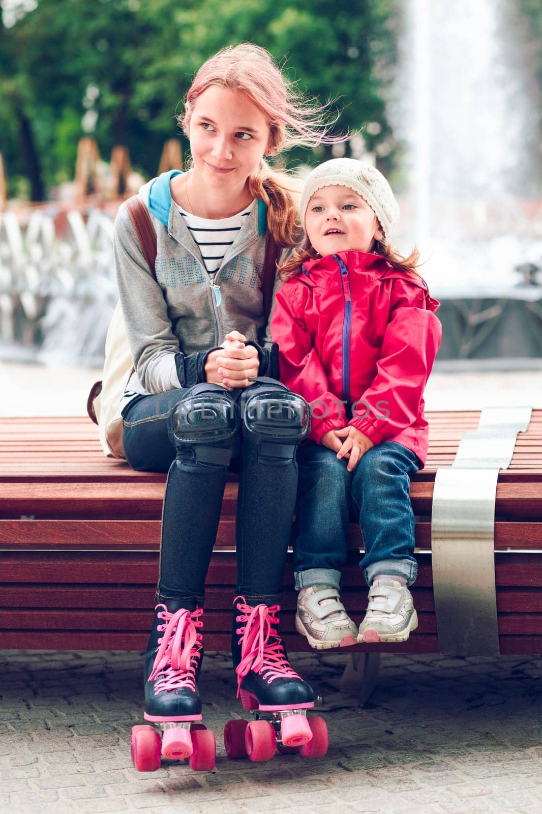 Sisters sitting on bench in a town