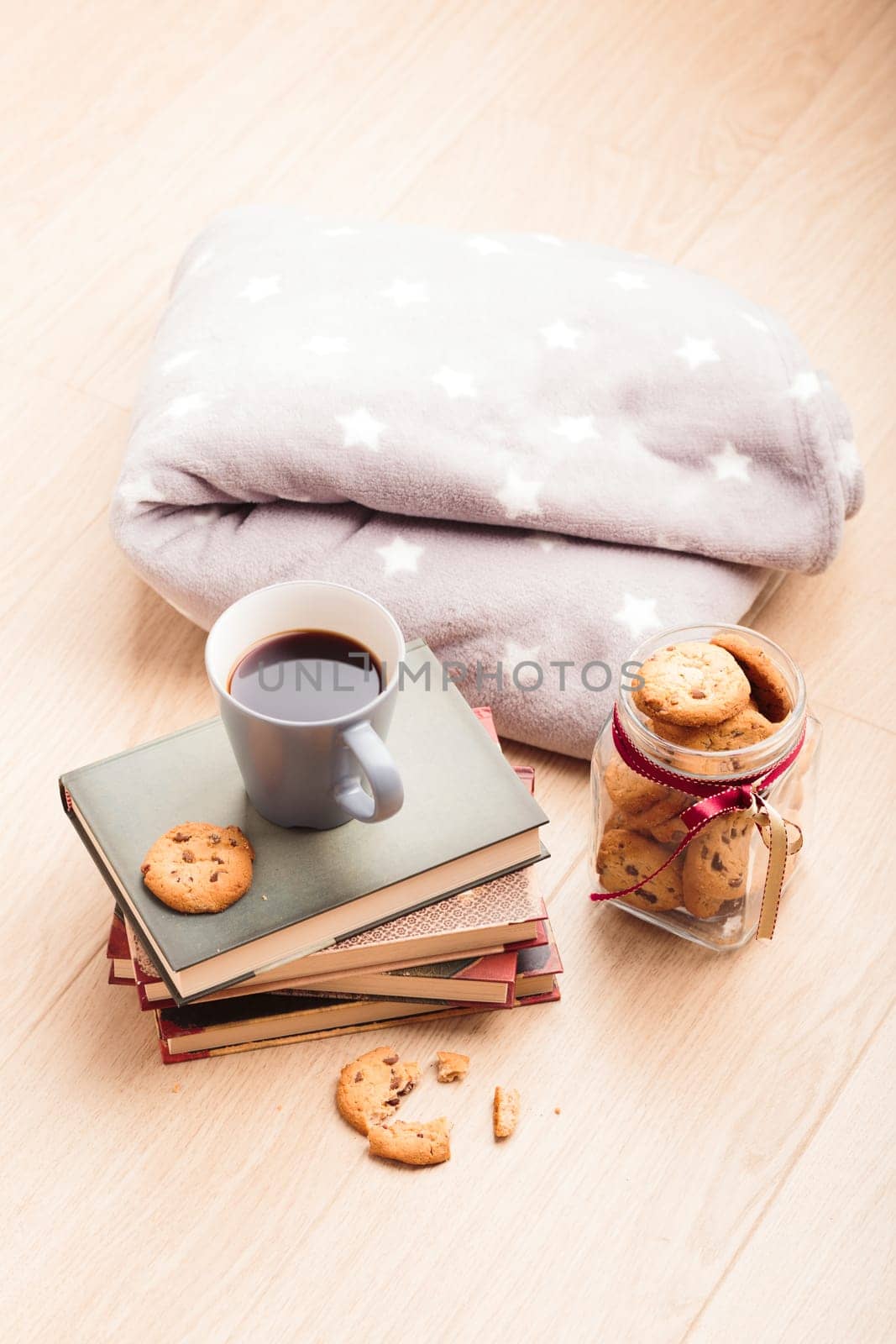 A few books with cup of coffee and cookies on wooden floor