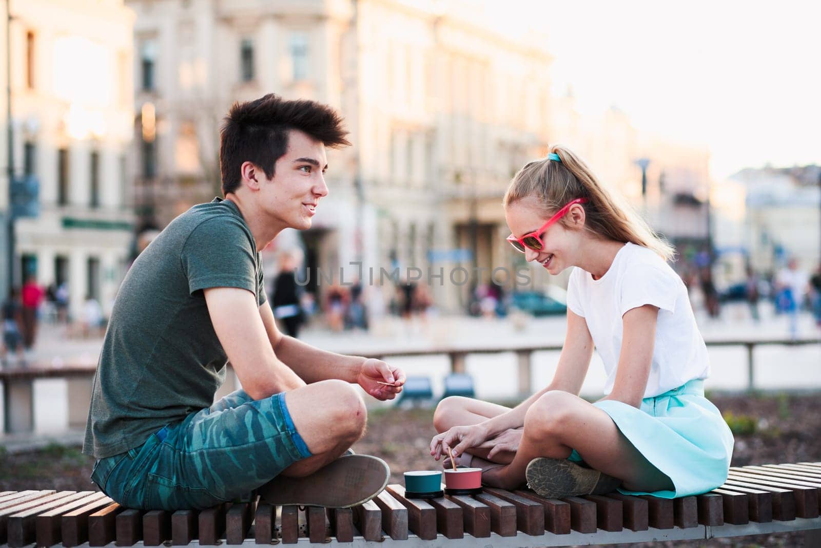 Girl and boy spending time together in the city centre eating ice cream on a summer day