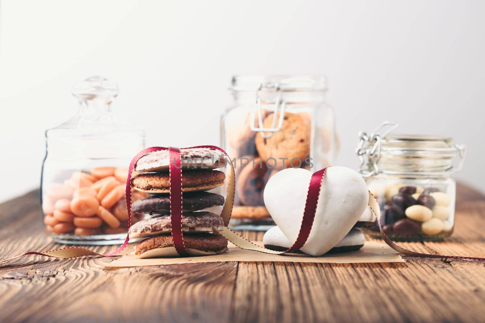 Gingerbread cookies, candies, cakes, sweets in jars on wooden table
