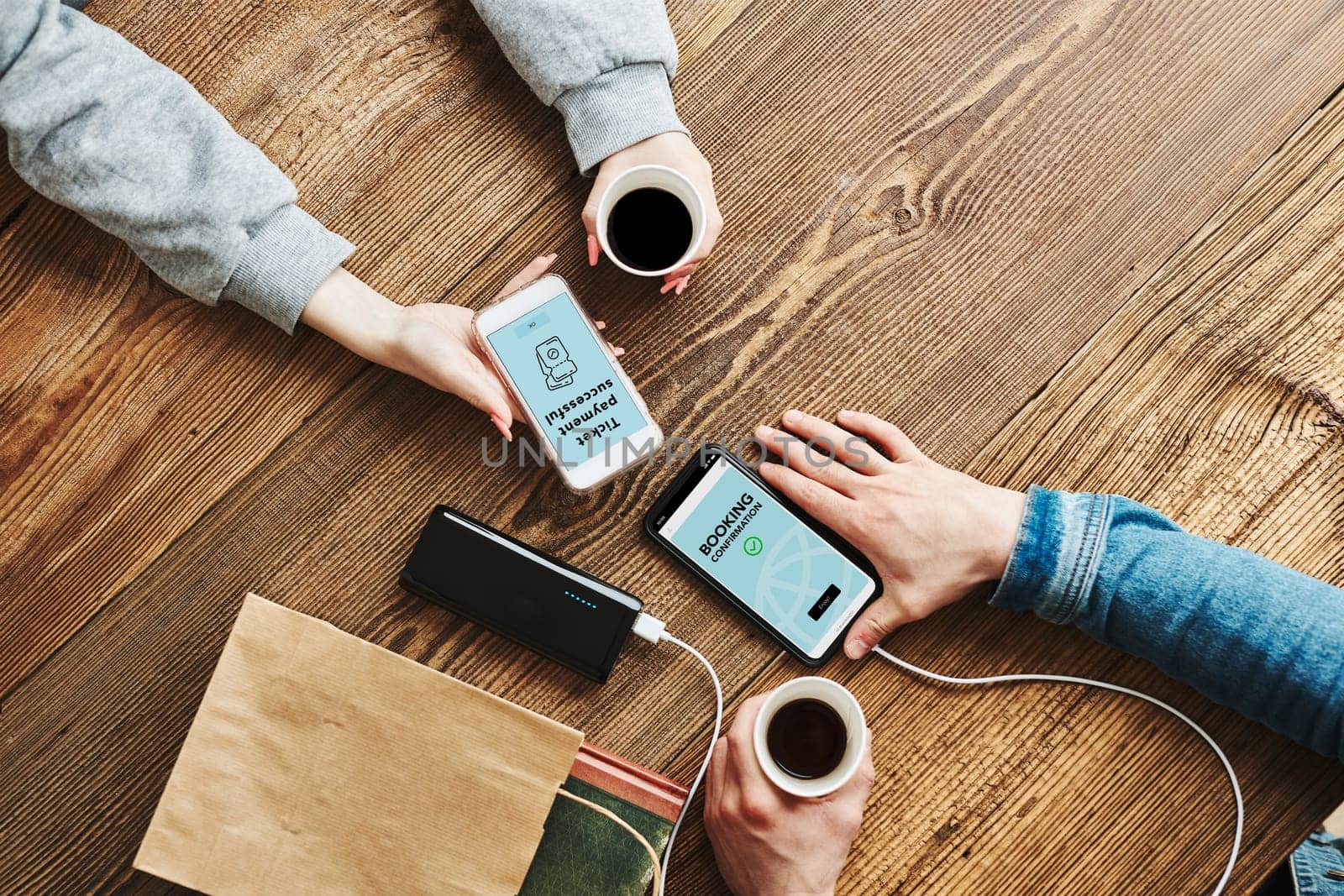 Online shopping. Booking online. Buying tickets online. Ordering product in online shop using smartphone. Order confirmation on screen. Online banking. People paying online. Paying for online shopping while charging mobile phone from powerbank in coffee shop