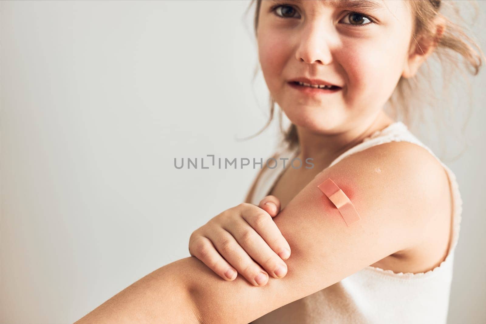 Little girl feeling pain having some side effects after vaccination. Redness, swelling, aching limbs and headache as reaction after vaccination. Getting a first injection. Healthy and medical concept