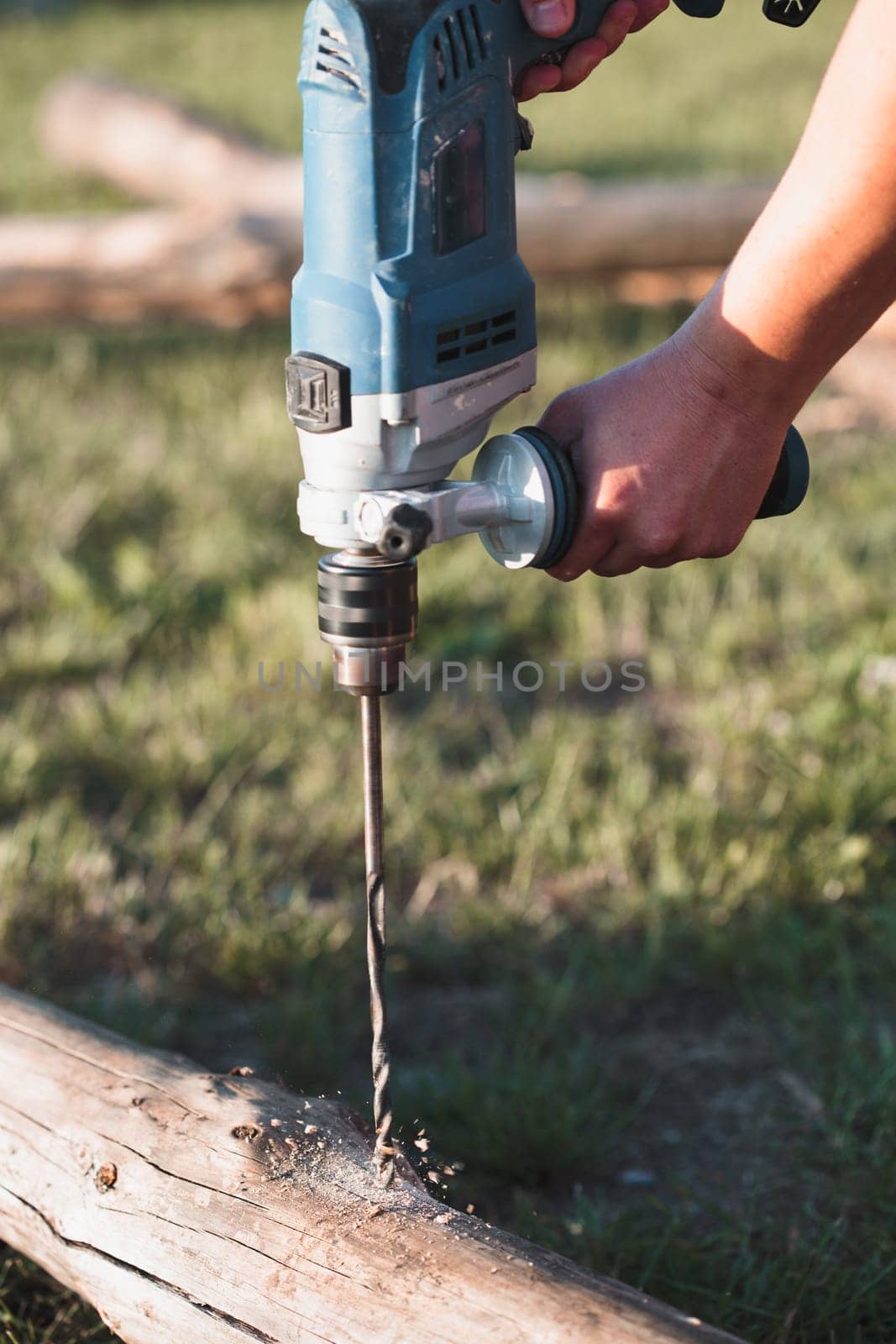 Man drilling hole in timber while working in garden