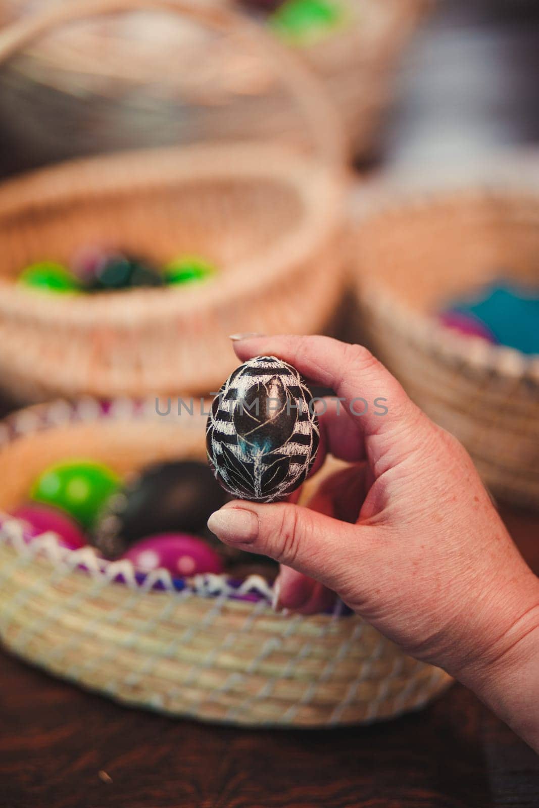 Woman decorating the Easter eggs by scratching patterns on dyed eggs. Traditional Easter time, spring time, new beginnings. Candid people, real moments, authentic situations