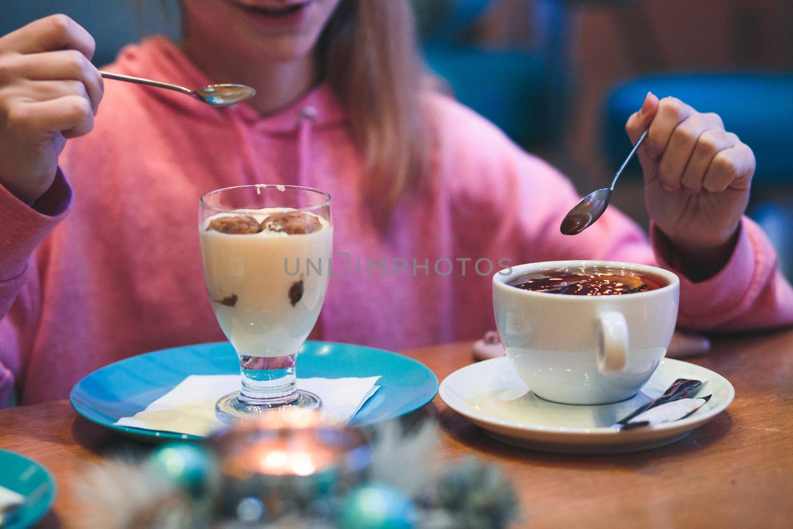 Girl eating a dessert and drinking a tea in coffee shop. Candid people, real moments, authentic situations