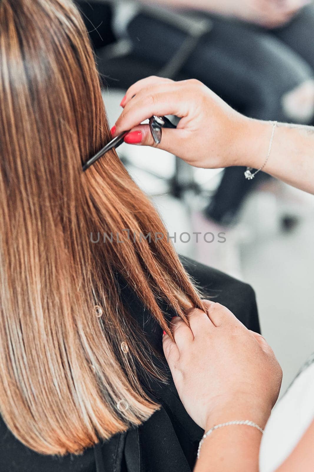 Hairdresser styling dyeing combing womans hair. Young woman working as a hairdresser in hair salon. Real people, authentic situations