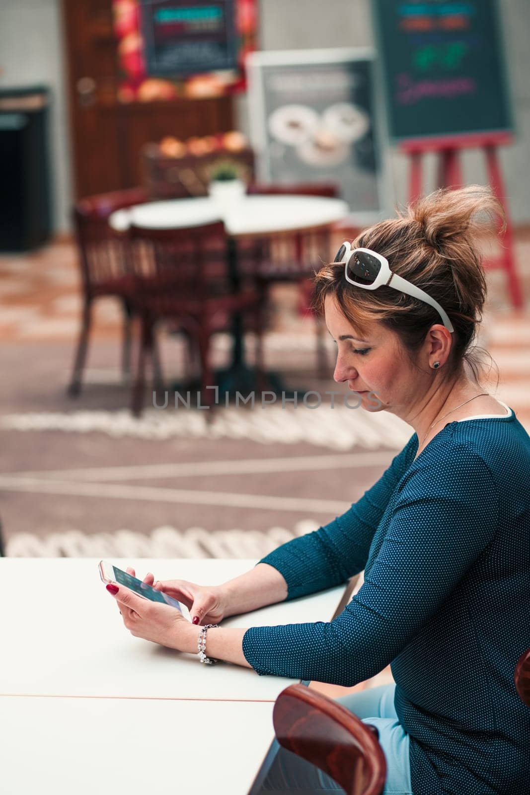 Young woman using mobile phone sitting by a table in cafe