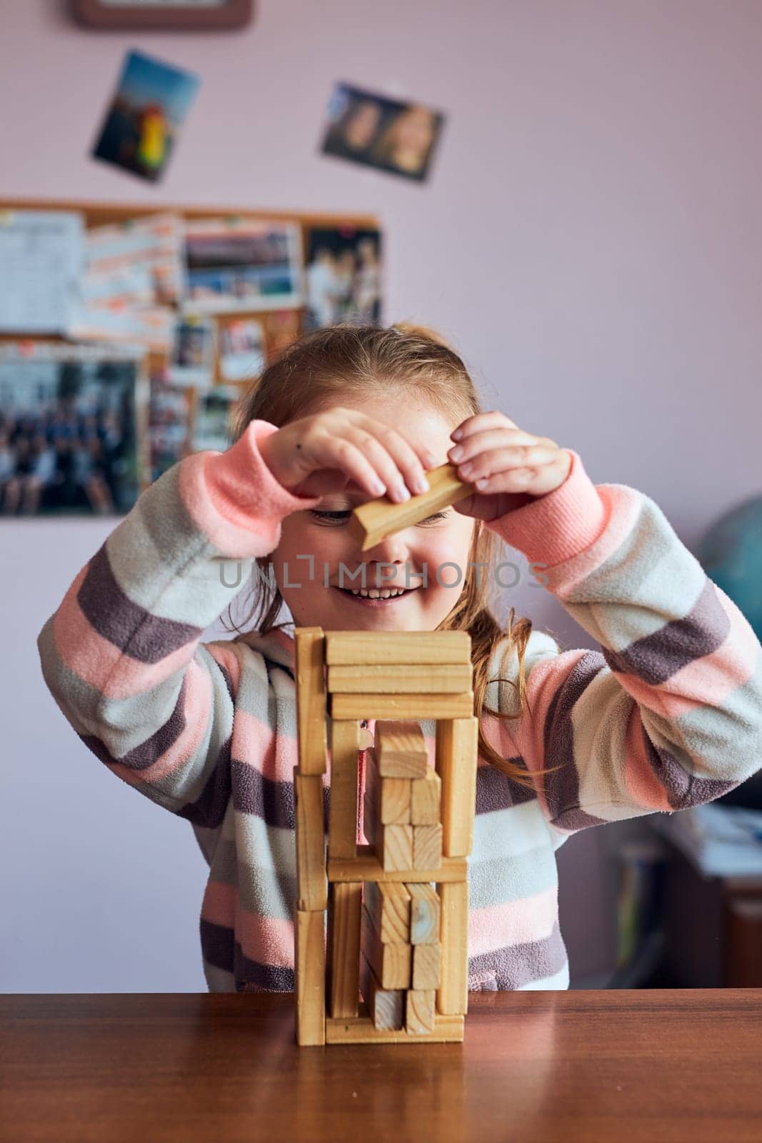 Little girl preschooler playing with wooden blocks toy building a tower. Concept of building a house
