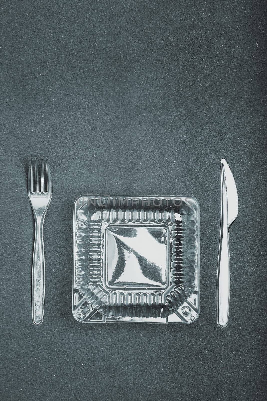 Plastic box and cutlery over dark background. Collecting plastic waste to recycling. Concept of plastic pollution and too many plastic waste. Copy space at the top