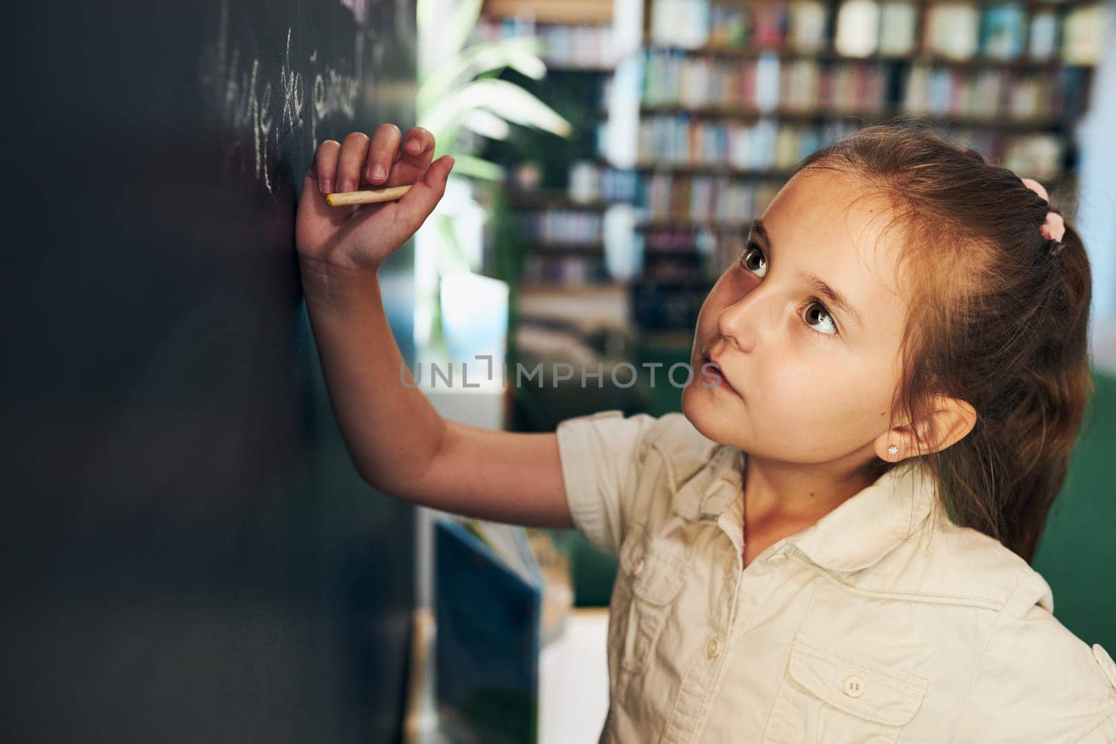 Little girl writing on blackboard. Smart student put solve on chalkboard. Back to school. Child having class. Schoolgirl learning at primary school. Elementary education