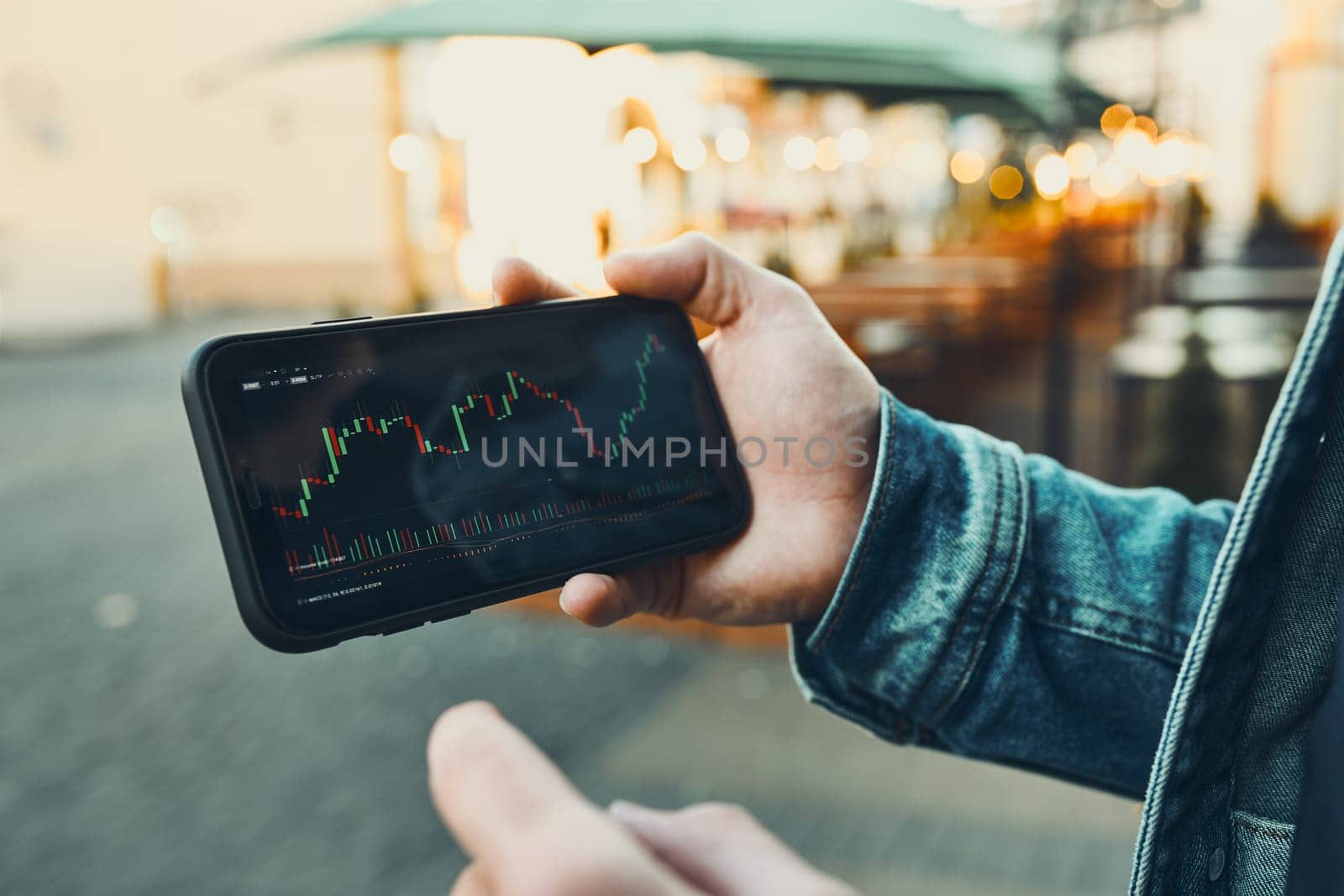 Person investing trading on stock cryptocurrency market using investing application on smartphone. Stock market investment in hand. Trader holding mobile phone looking at candle chart