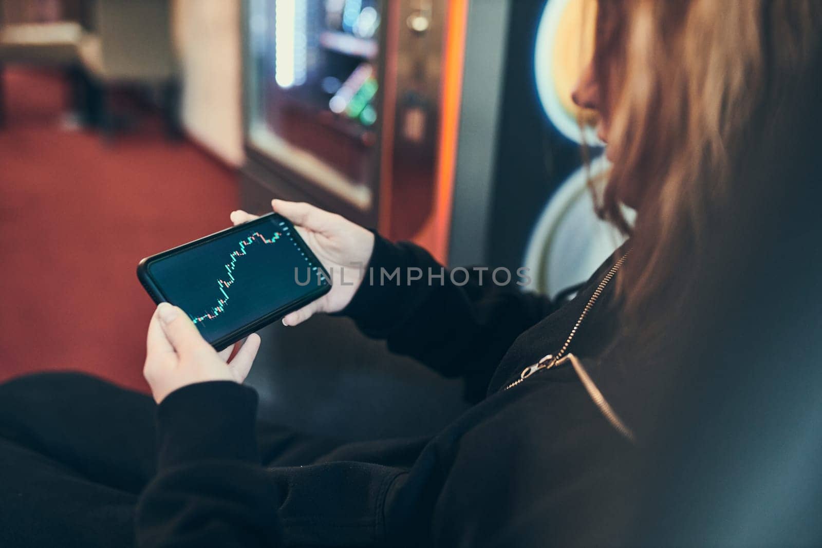 Person investing trading on stock cryptocurrency market using investing application on smartphone. Stock market investment in hand. Trader holding mobile phone looking at candle chart