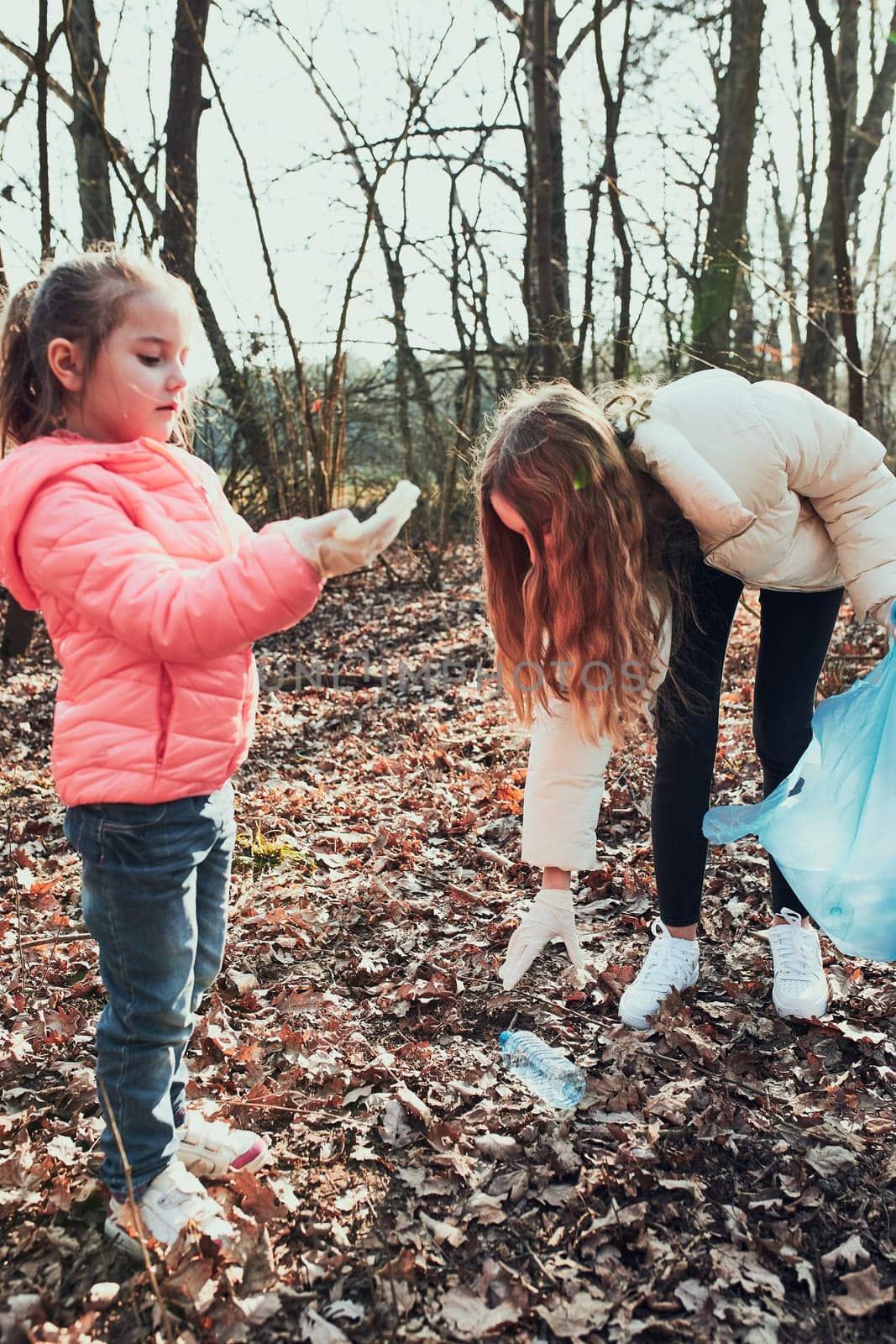 Family cleaning up a forest. Volunteers picking plastic waste to bags. Concept of plastic pollution and too many plastic waste. Environmental issue. Environmental damage. Responsibilitiy for environment. Real people, authentic situations