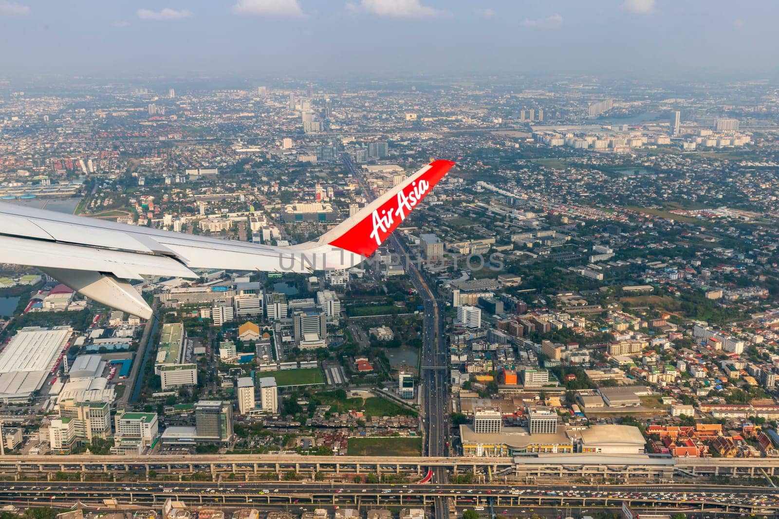 Bangkok Thailand - March 28, 2019: AirAsia (a popular low-cost airline)'s aircraft wing just took off from Don Mueang Airport. The ground image shows the city of Bangkok, the capital of Thailand.