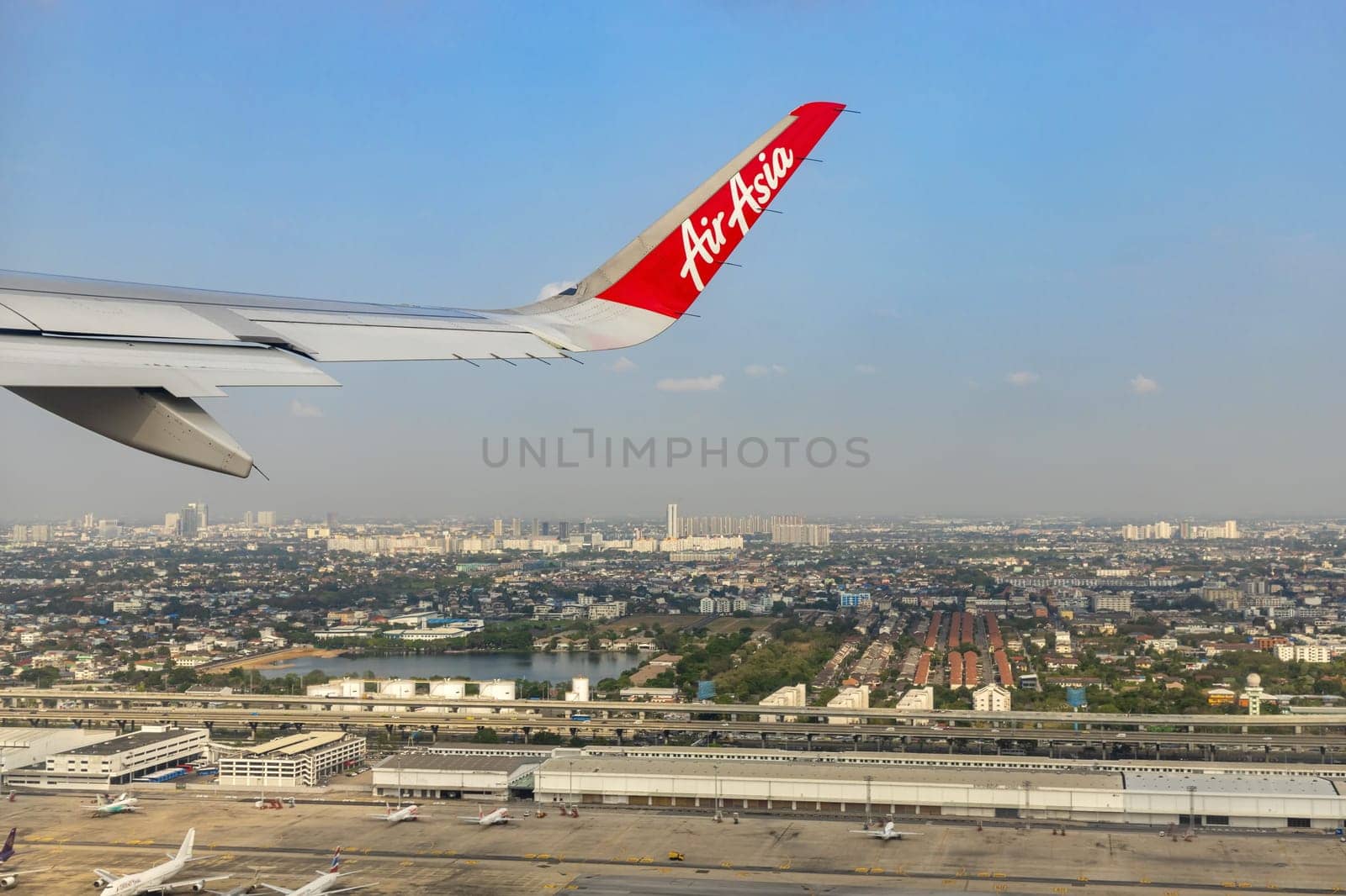 Bangkok Thailand - March 28, 2019: AirAsia (a popular low-cost airline)'s aircraft wing just took off from Don Mueang Airport. The ground image shows the city of Bangkok, the capital of Thailand.