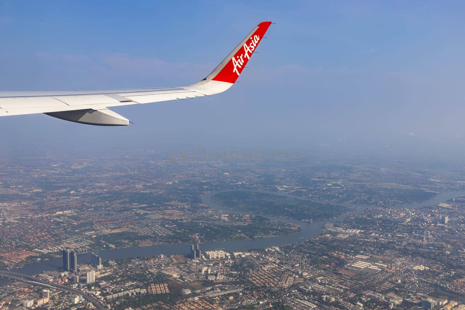 Bangkok Thailand - March 28, 2019: AirAsia (a popular low-cost airline)'s aircraft wing just took off from Don Mueang Airport. The ground image shows the city of Bangkok, the capital of Thailand.