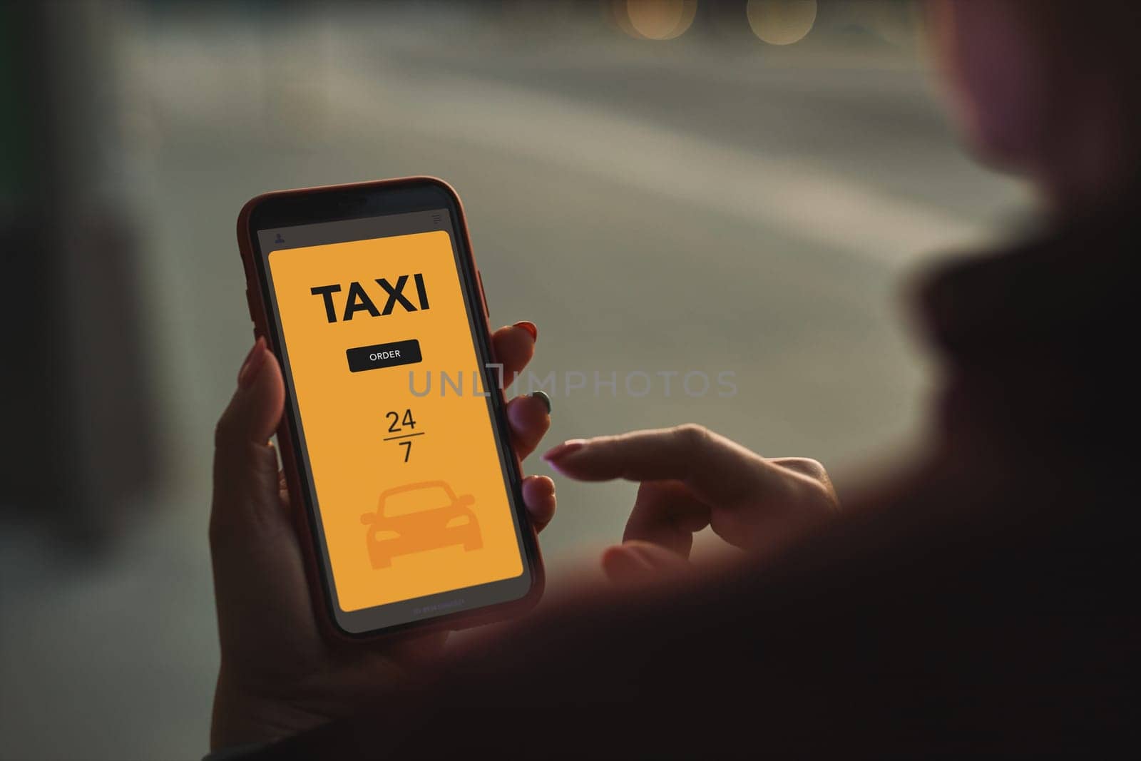 Woman ordering taxi online using mobile app on smart phone. Booking taxi using application online. Arranging taxi ride in downtown city street. Car sharing. Taxi service on mobile. City traffic lights at night in background