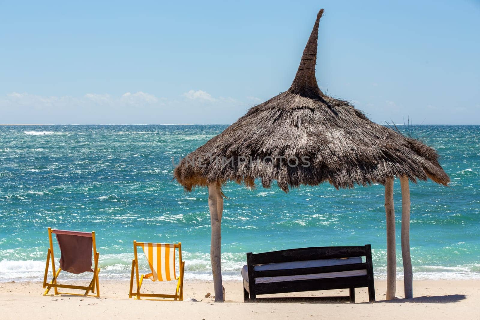 Tranquil and beautiful day on Anakao beach in Madagascar, with a clear blue sky, a comfortable sun lounger, and a colorful parasol for your ultimate relaxation. Toliara, Madagascar