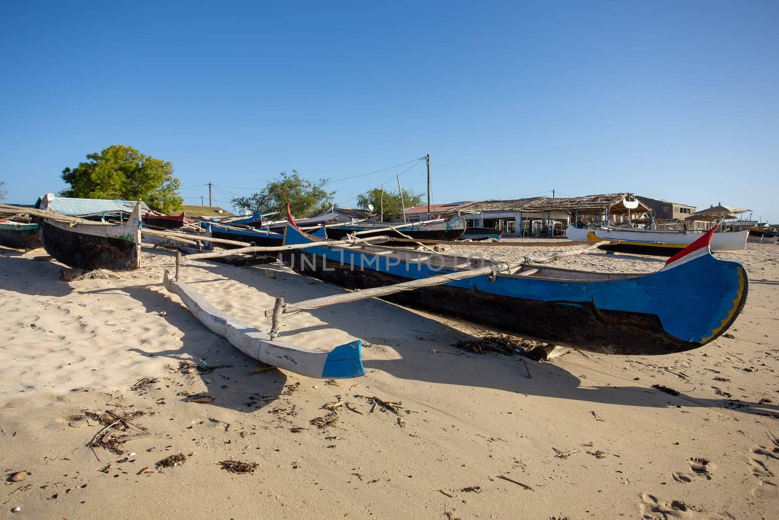 An empty wooden traditional fishing boat on the shore, waiting for the next catch of the day in Madagascar. Traditional wooden fishing boats on the tropical beach of Anakao, Toliara, Madagascar.