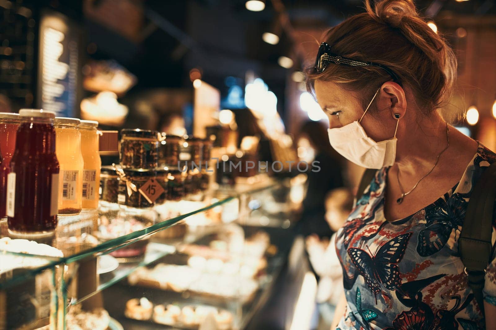 Young woman shopping in grocery store in the evening, wearing the face mask to avoid virus infection and to prevent the spread of disease in time of coronavirus