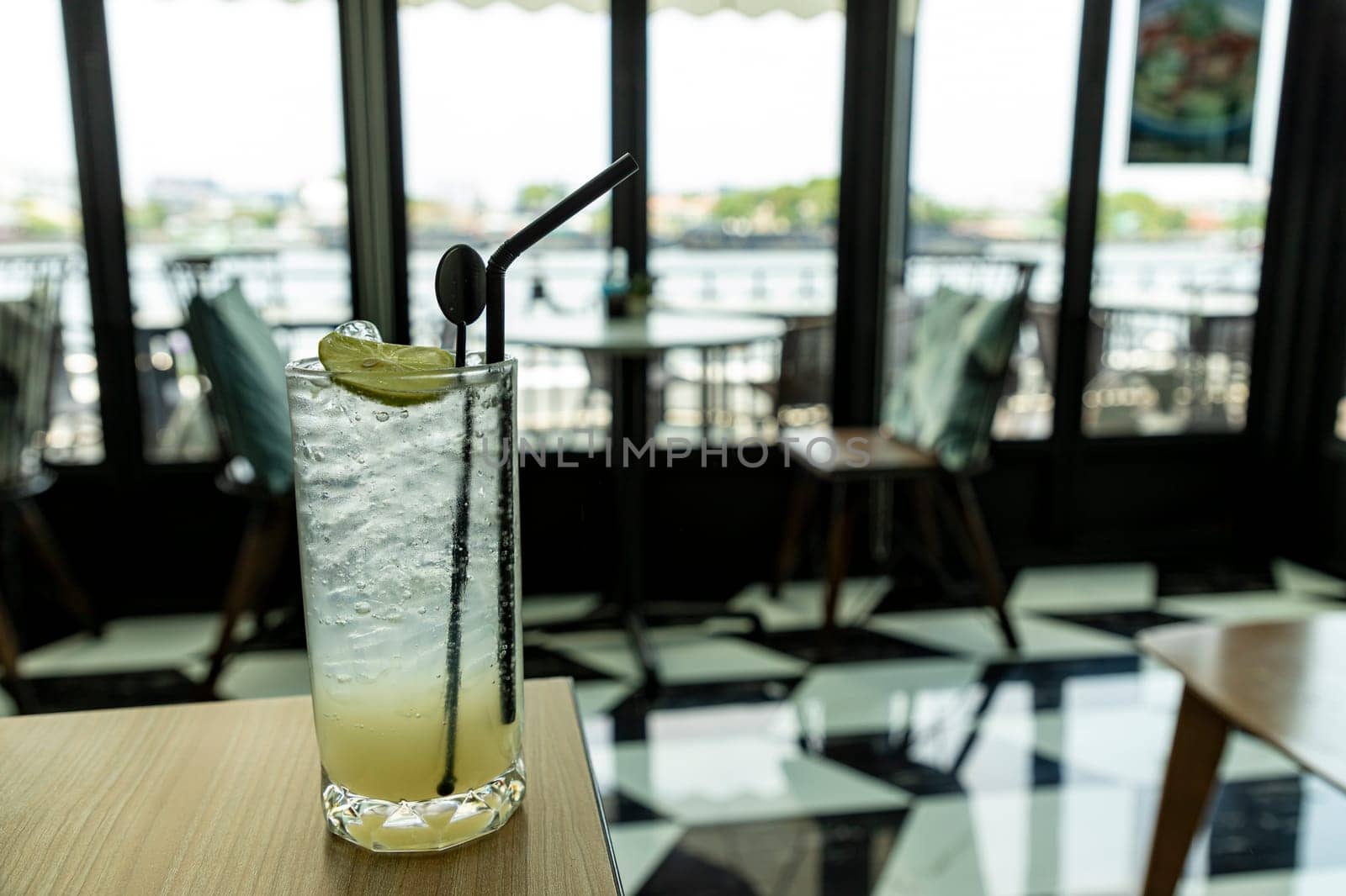 Lemonade looks delicious, cool and refreshing in a classic style cafe by the river. The atmosphere is pleasant to sit and listen to chill music for a long time. It is a horizontal picture.