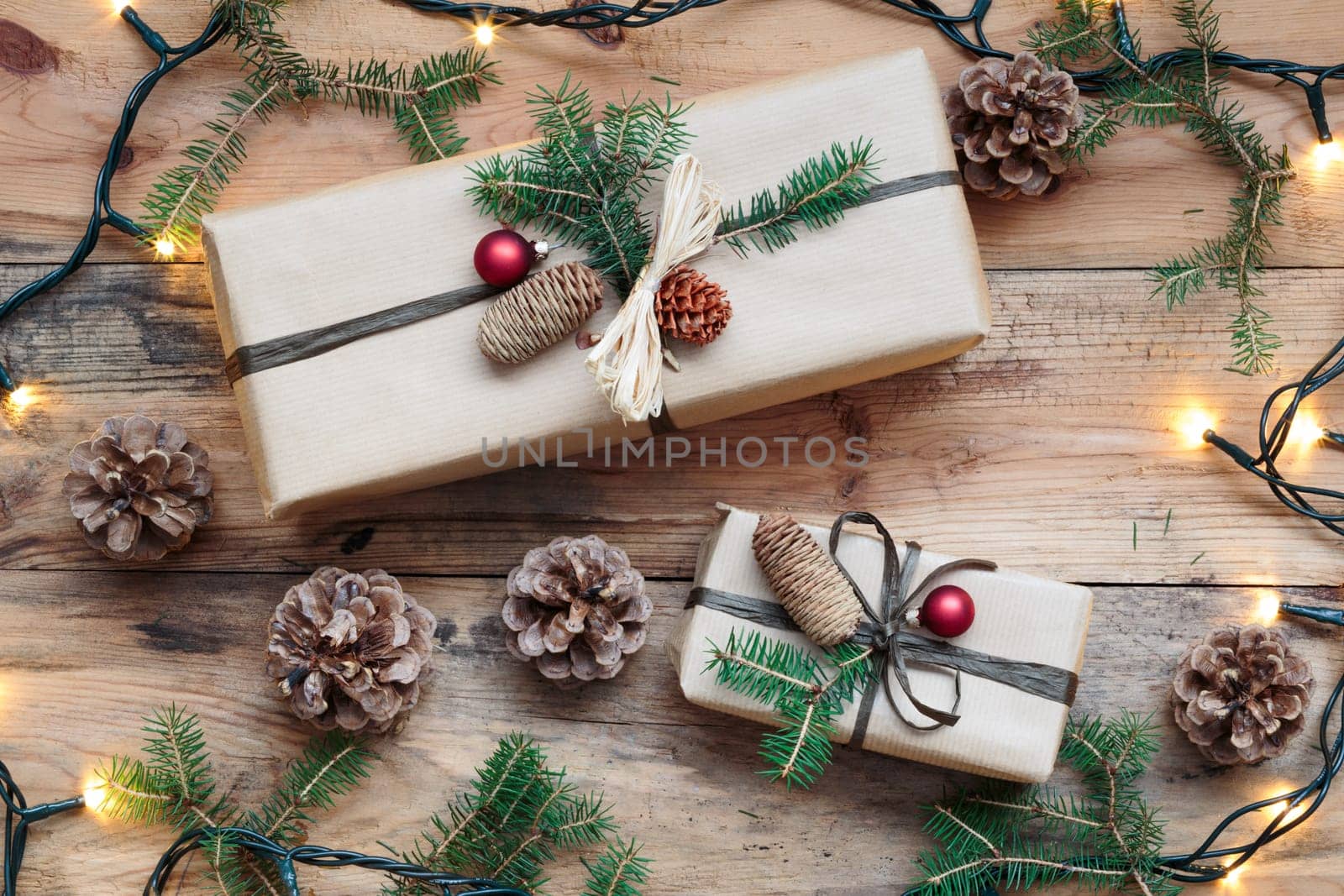 Christmas presents under a Christmas tree. Gifts wrapped in paper decorated with cones and pine twigs put on wooden floor. View from above. Copy space for text at top of image