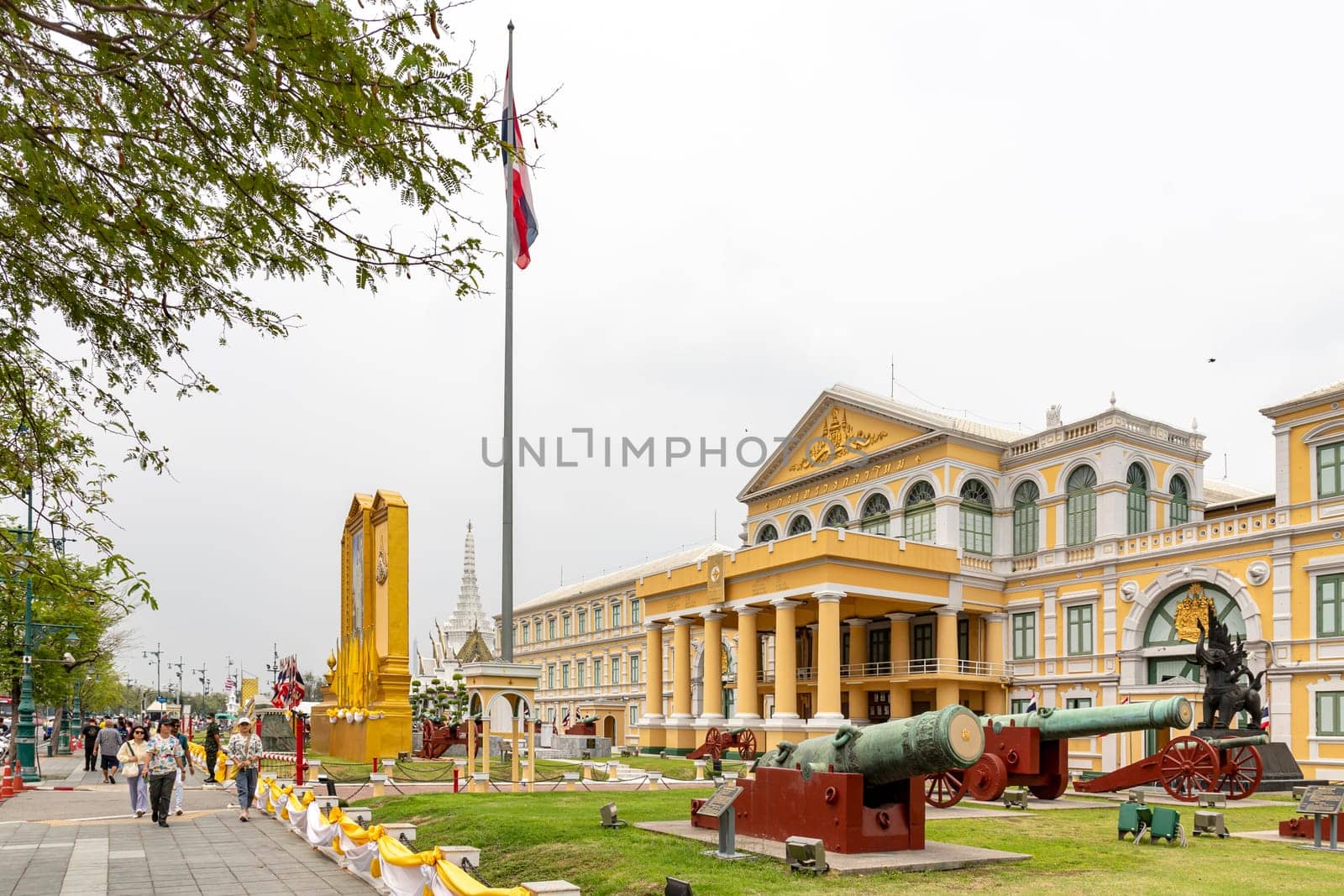 Bangkok,Thailand- April16, 2023: Building of the Ministry of Defense of Thailand​ It is a European-style building, yellow, with a white line. In front of the building there are 40 antique real cannons