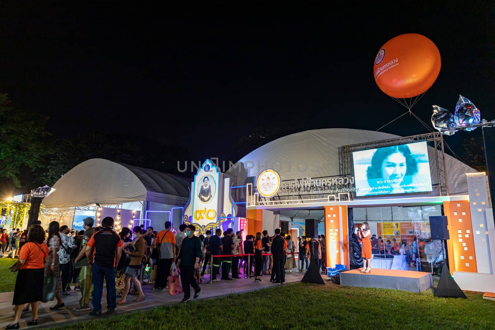 Bangkok, Thailand - Dec 8, 2022 : Many people queue up to watch the exhibition of state-owned enterprises in the Red Cross Fair at Lumpini Park at night. Between 8-18 December 2022, motion blur
