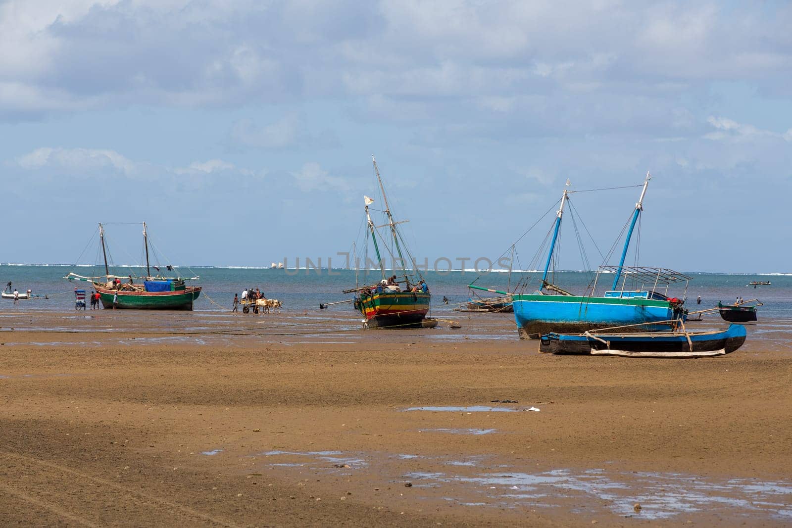 Toliara, Madagascar - November 21st 2022: Fishing boat stranded on the dry port during low tide with Malagasy people around.