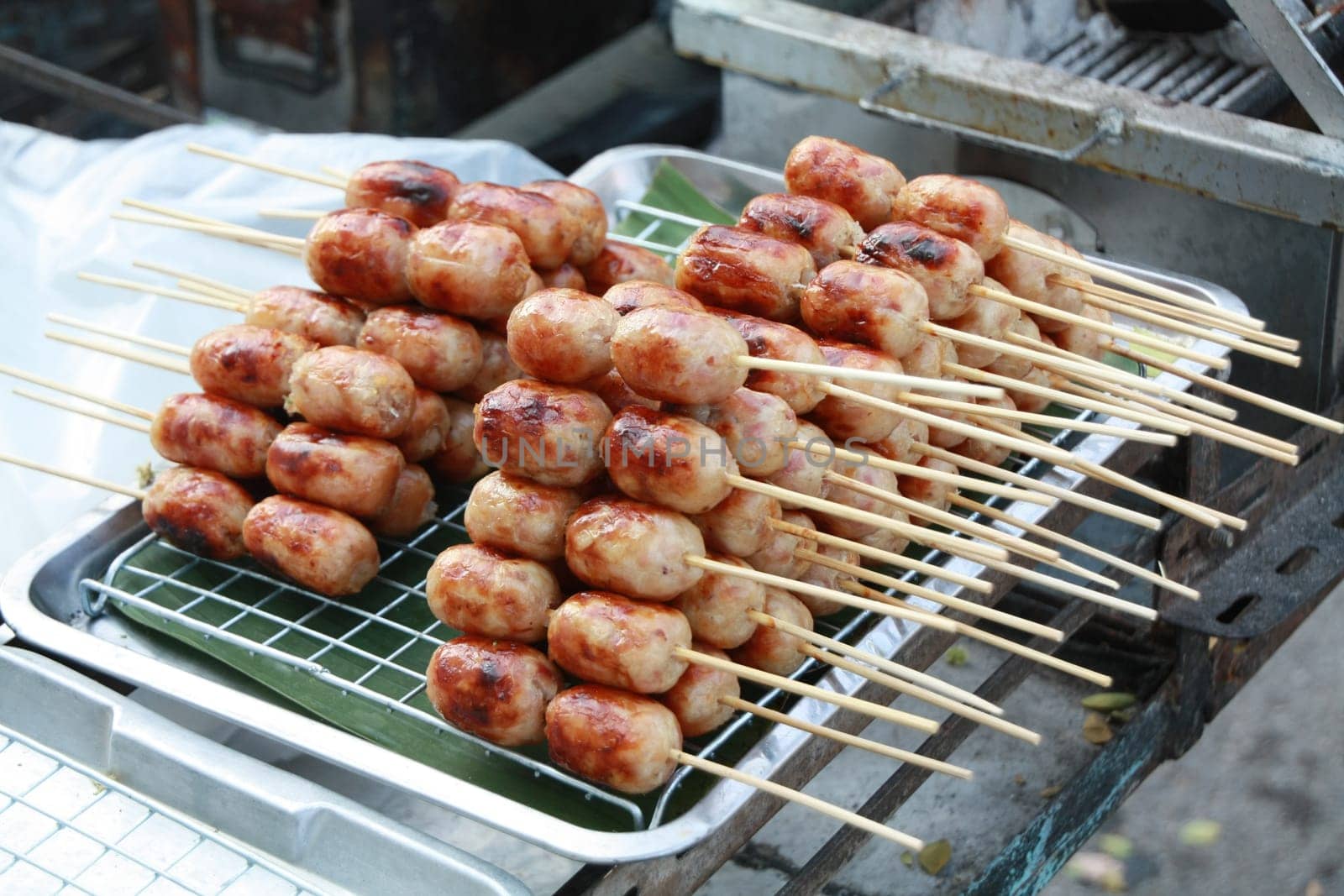 Isaan Sausage, a very popular street food in Thailand. Easy to buy, cheap price, delicious taste made from pork stuffed with sour seasoned rice and pork, served with ginger, fresh chilli, and lettuce.