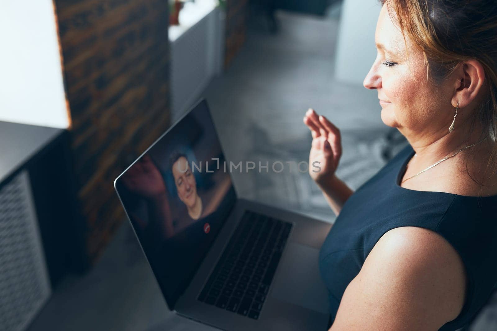 Woman having business video call on laptop in office. Mature busy woman remotely working from office. Female manager using digital devices. Remote communication. Video calling. Remote work
