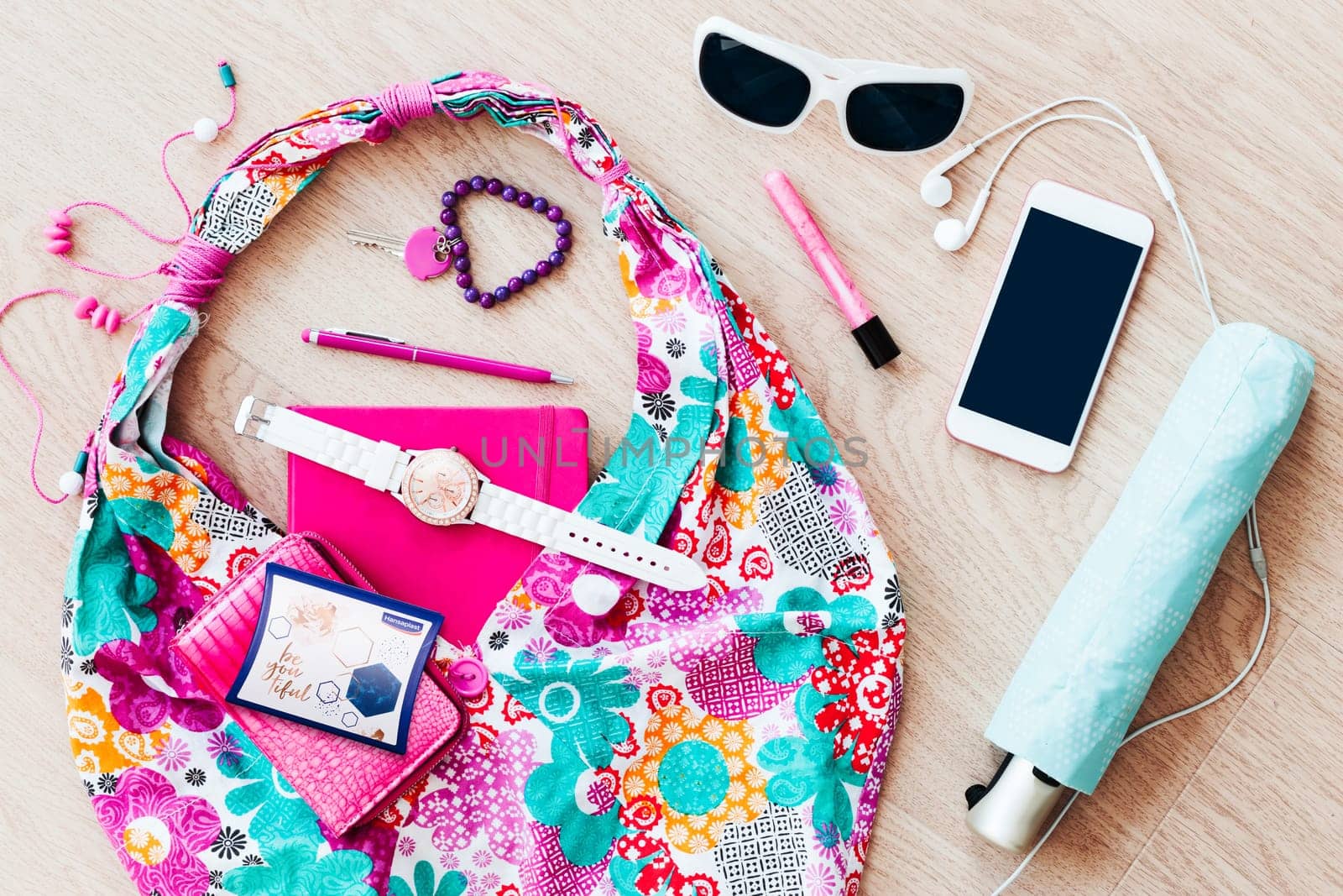 Smartphone sunglasses wallet notebook and other things pulled out of handbag put on a table