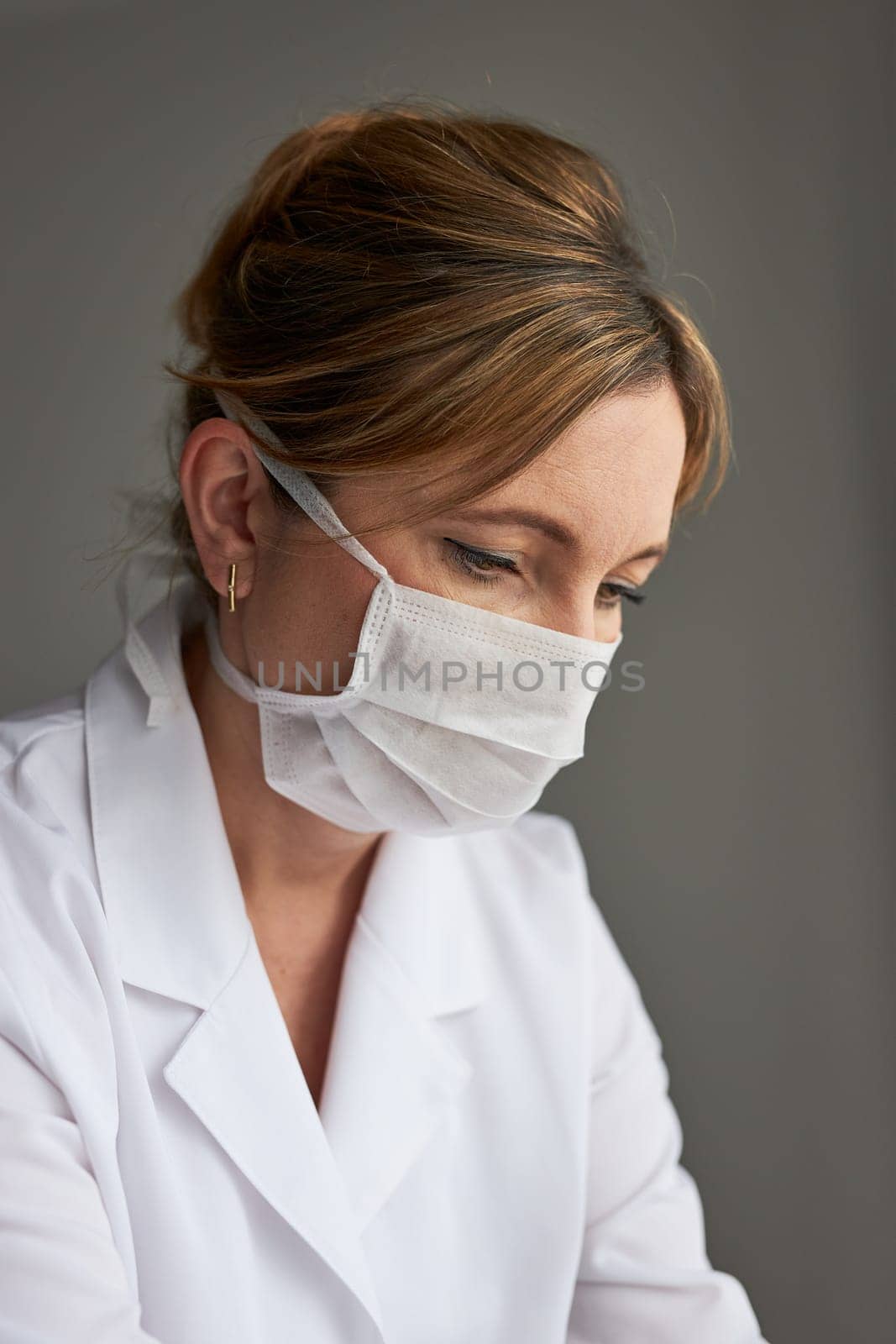 Doctor with face covered with mask. Portrait of young woman wearing the uniform and mask to avoid virus infection and to prevent the spread of disease. Real people, authentic situations