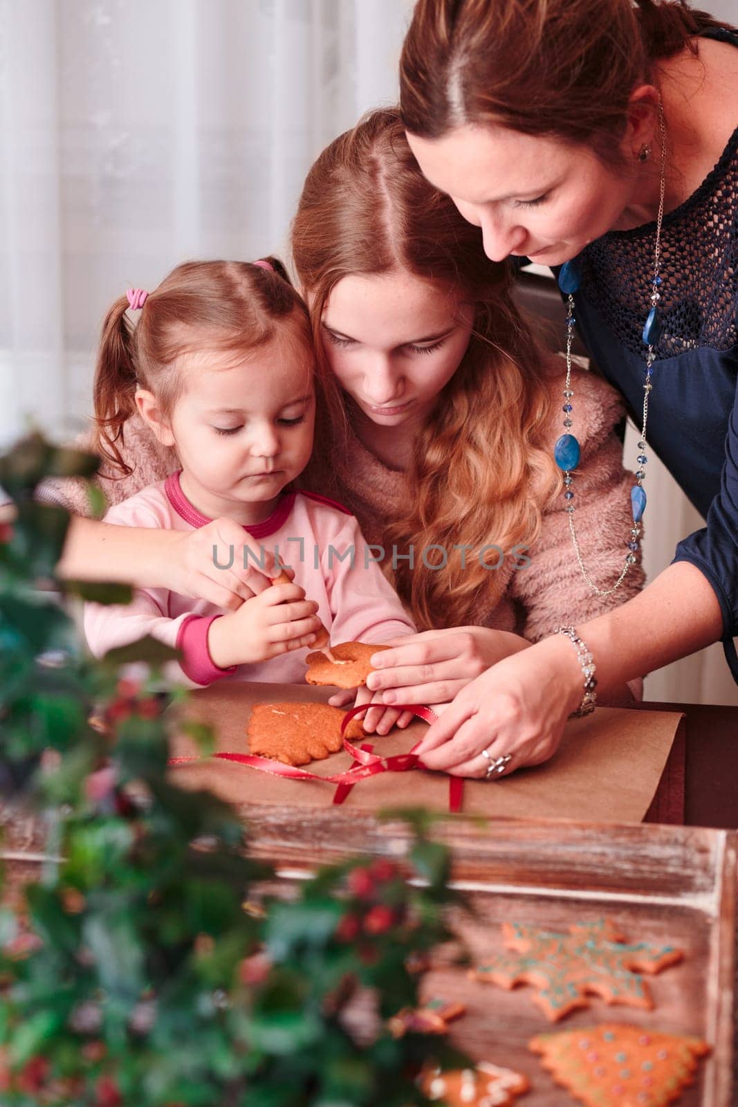 Family decorating baked Christmas gingerbread cookies with frosting