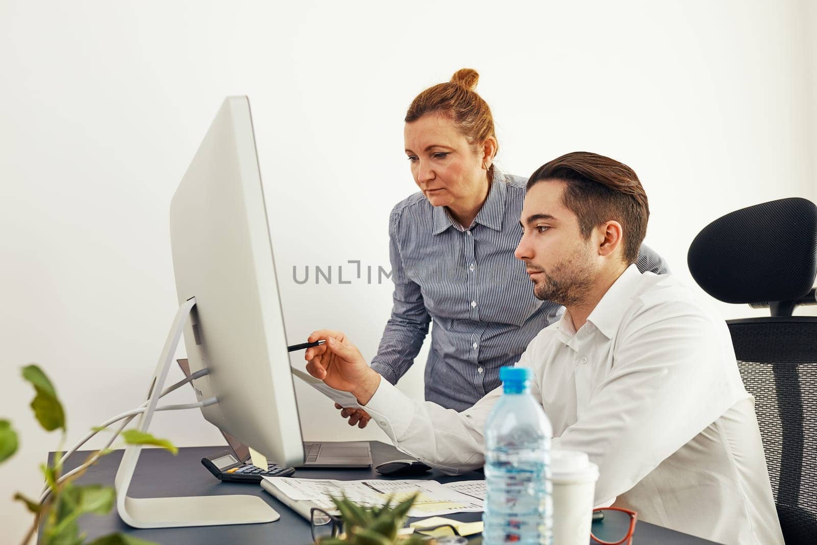 Business colleagues discussing financial data working together in office. People entrepreneurs working with charts and tables on computer. Two people working together. Workmates talking about project