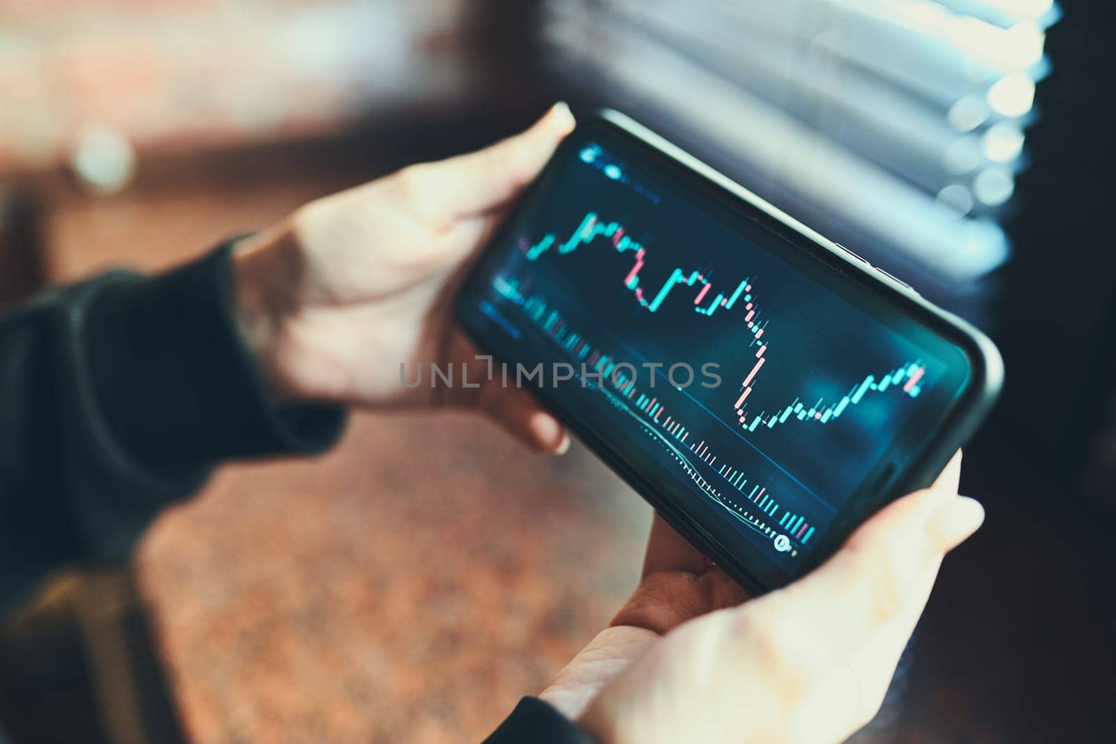 Person investing trading on stock cryptocurrency market using investing application on smartphone. Stock market investment in hand. Trader holding mobile phone looking at candle chart