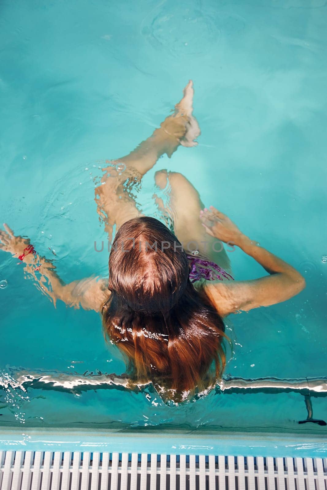 Young woman swimming and relaxing in swimming pool. Candid people, real moments, authentic situations