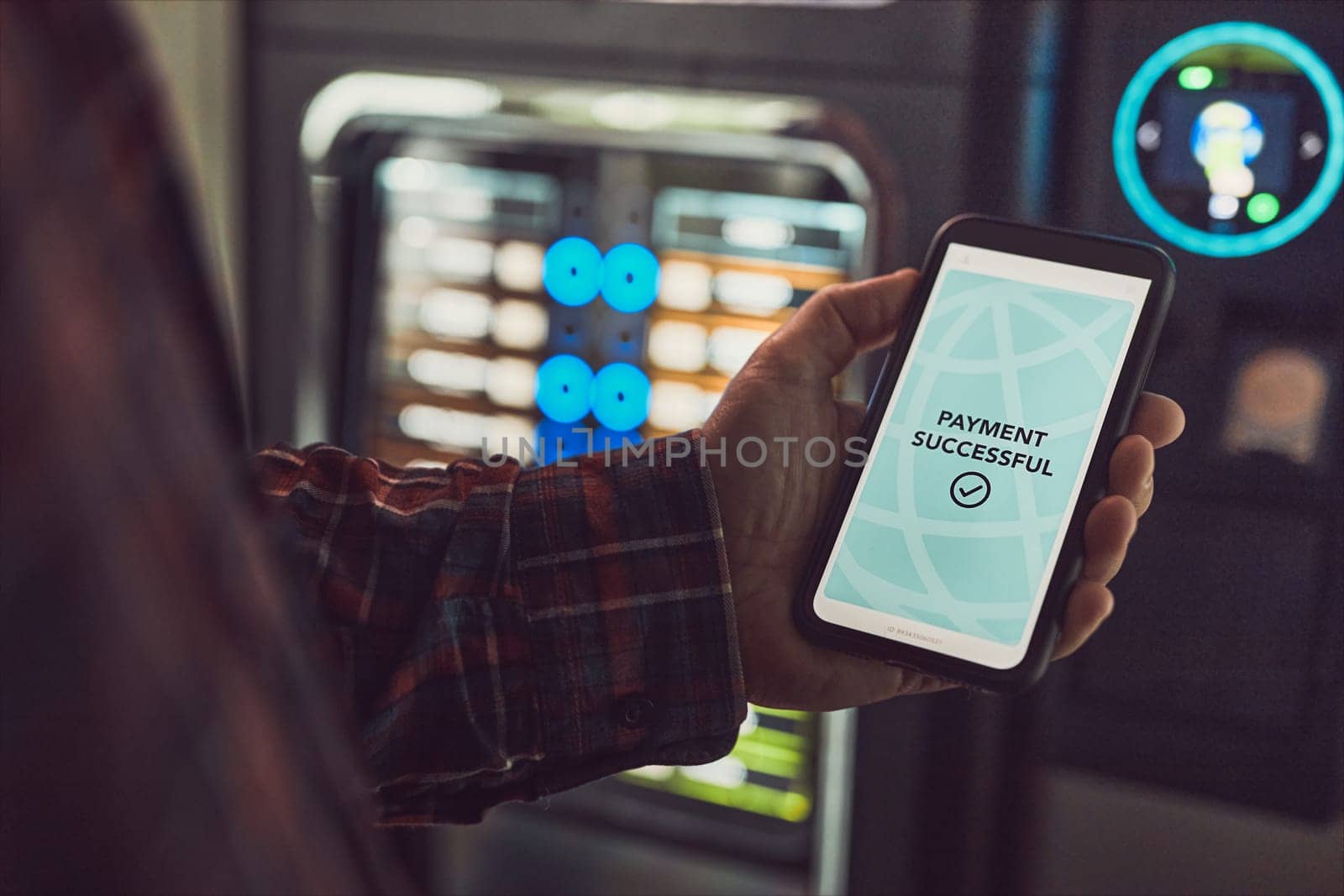 Consumer paying for product at vending machine using contactless method of payment with mobile phone. Man using payment app on smartphone to buy product. Male hand holding smart phone with payment confirmation on screen