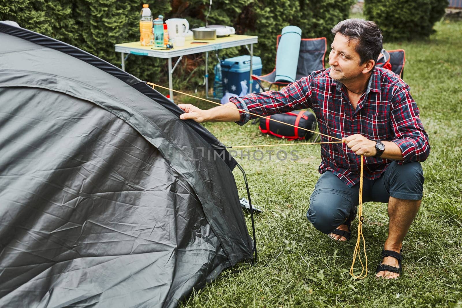 Man putting up a tent at camping during summer vacation. Preparing campsite to rest and relax. Spending vacations outdoors close to nature