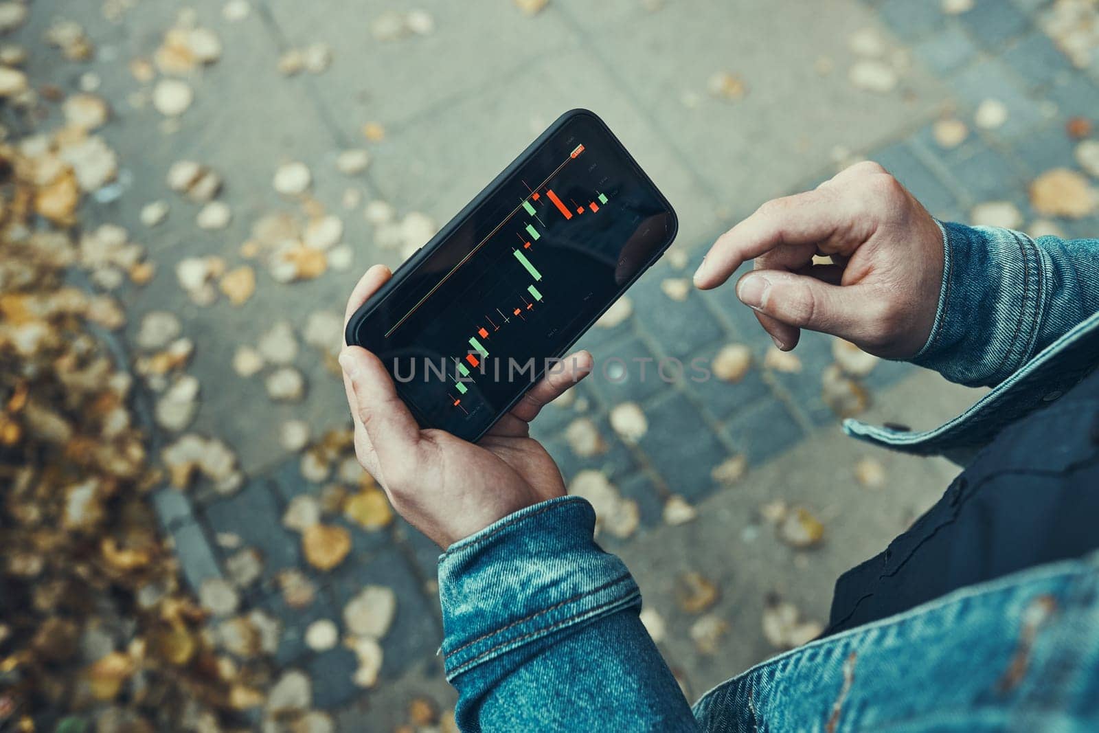 Person investing trading on stock cryptocurrency market using investing application on smartphone. Stock market investment in hand. Trader holding mobile phone looking at candle chart