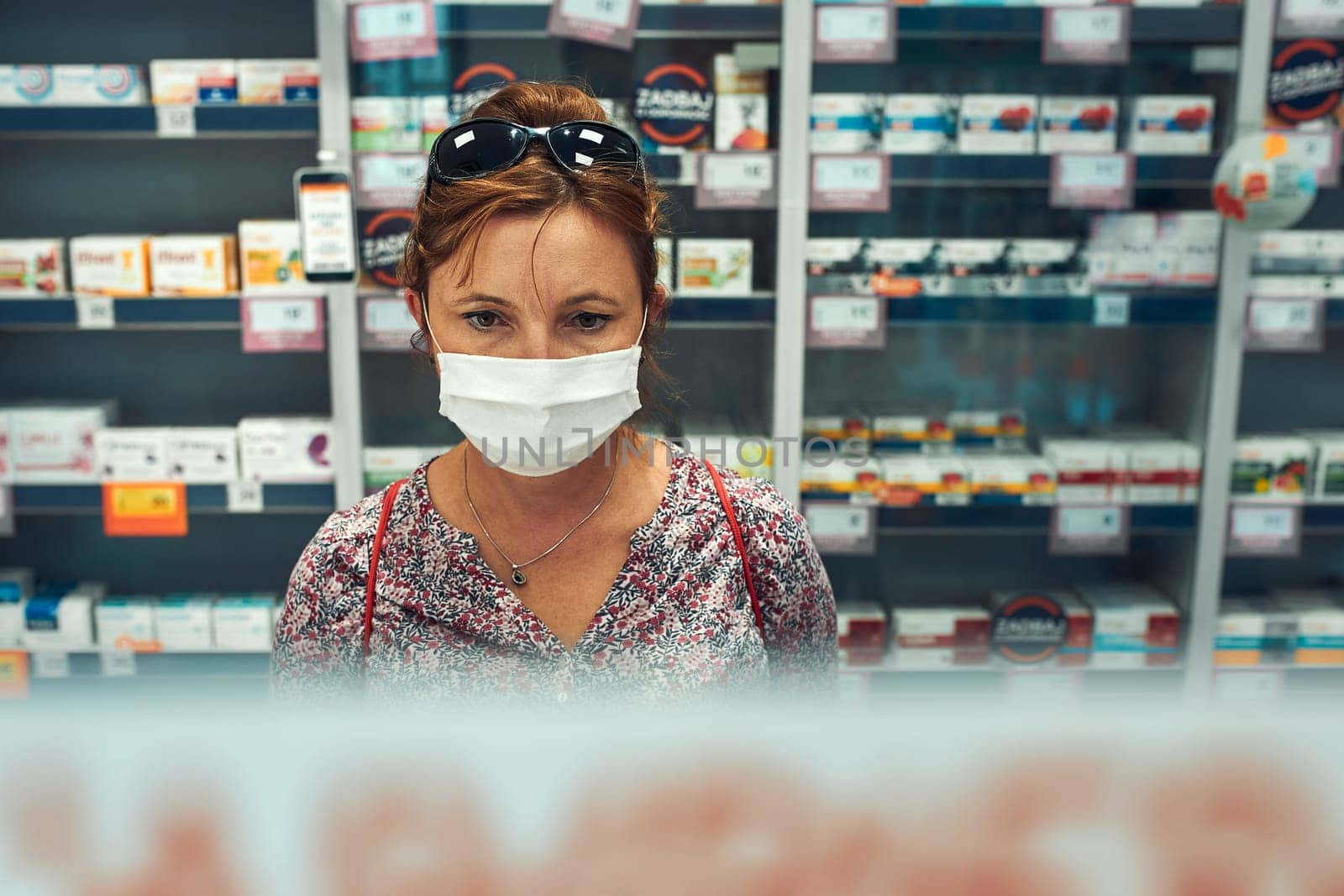 Woman shopping at pharmacy, buying medicines, wearing face mask to cover mouth and nose during pandemic coronavirus outbreak