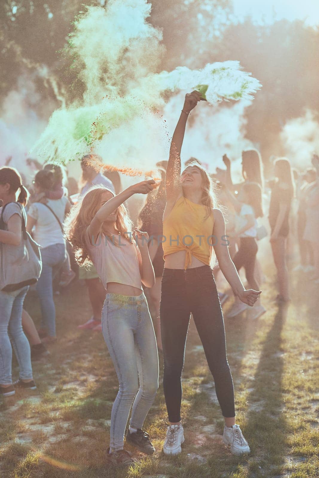 Portrait of happy smiling young girls with colorful paints on faces and clothes. Two friends spending time on holi color festival
