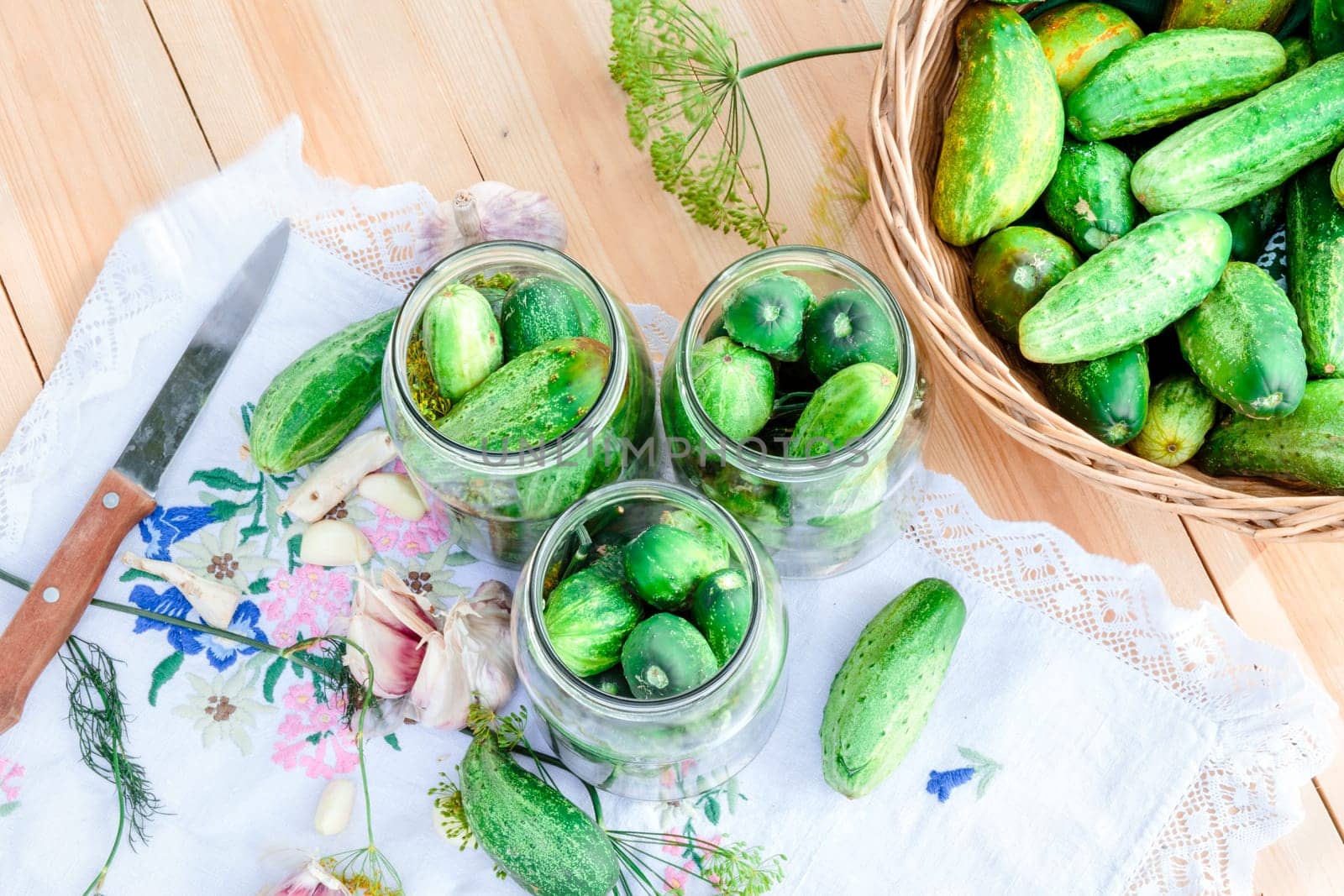 Pickling the cucumbers with home garden vegetables and herbs, fresh vegetables picked straight from field, collected on wooden table outdoors. View from above
