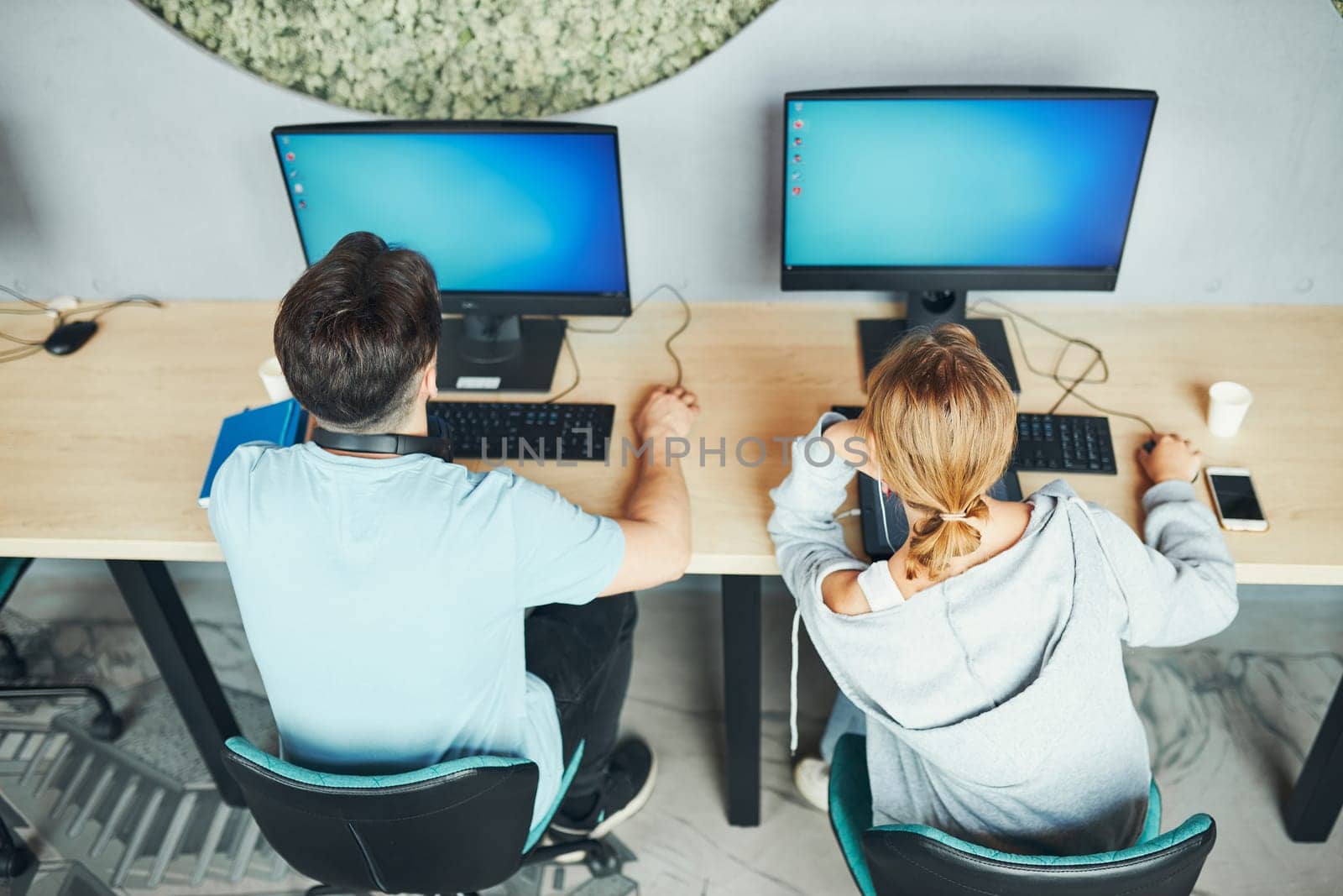 Students learning in computer classroom. Young man preparing for test on computer. Girl writing essay and making notes using computer. Focused students studying for college exams. Students discussing and learning together sitting at desk. Back to school