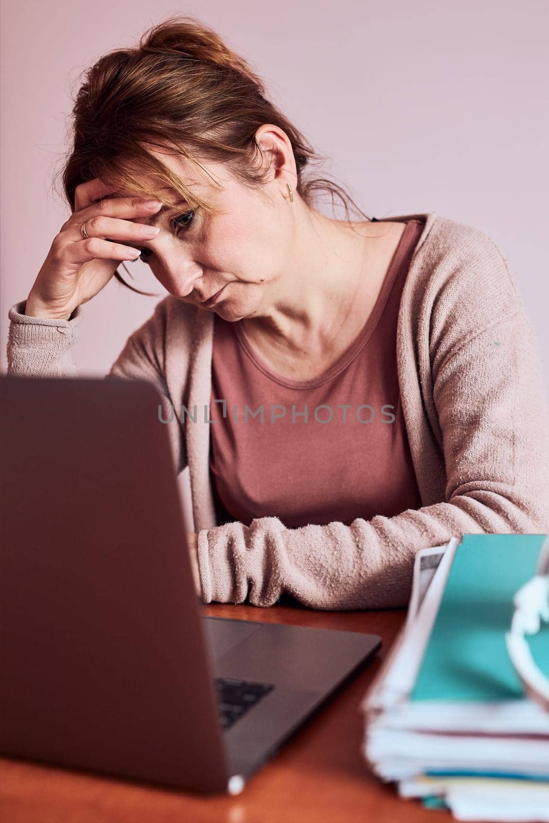 Woman focused on her work working hard doing her job remotely on laptop from home. Woman sitting at desk in front of computer looking at screen. Concept of remote working