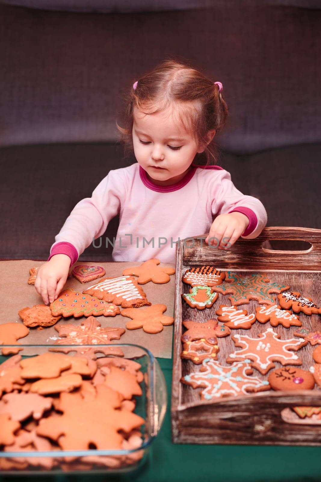 Little girl placing Christmas gingerbread cookies on wooden tray