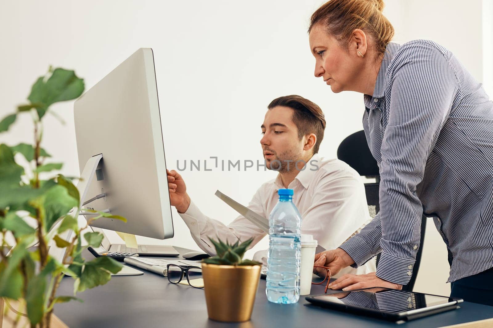 Business colleagues discussing financial data working together in office. People entrepreneurs working with charts and tables on computer. Two people working together. Workmates talking about project