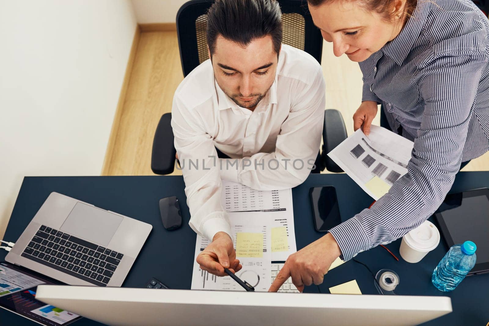 Business colleagues discussing financial data working together in office. People entrepreneurs working with charts and tables on computer. Two people working together. Workmates talking about project