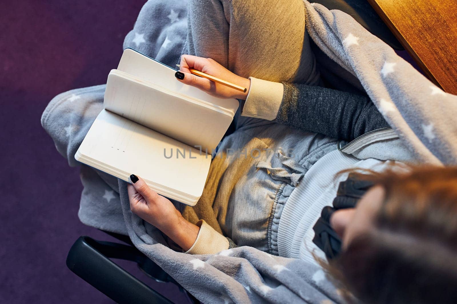 Student learning at home. Young woman making notes, reading and learning from notepad sitting in bed at home during quarantine
